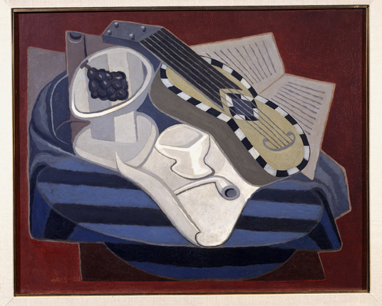 A Cubist painting, depicting a still life with a recognizable guitar with black-and-white inlays, a footed bowl, a pipe, some sort of manuscript, and another bowl with grapes, on a table covered with a blue-and-black striped cloth. While more representational than some other Cubist works, it's still undeniably in that style.