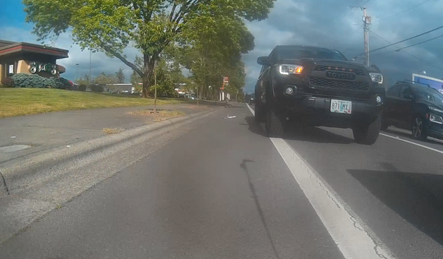 pickup edging into the bike lane long before a turn, several stopped cars in front of them