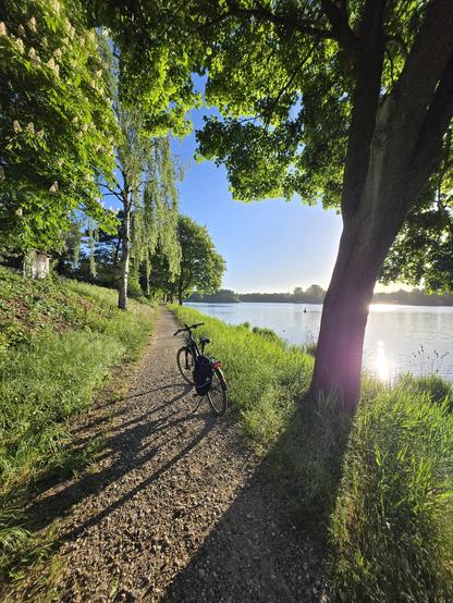 Fahrrad auf Wanderwege entlang eines Kanals. Die Sonne scheint.