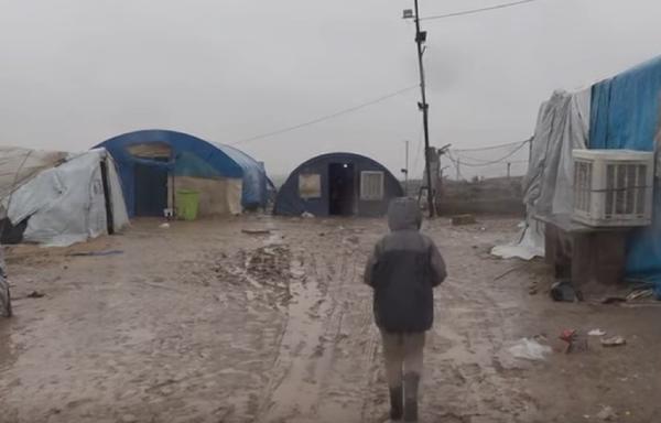 Un enfant au milieu de la boue d’un camp.