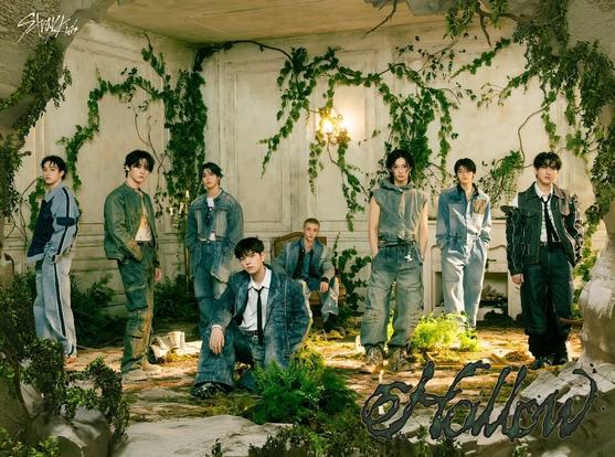 Teaser image for *Hollow* by Stray Kids, featuring the members wearing mostly denim outtfits, sitting or standing in a fancy but abandoned room that is being overtaken by greenery