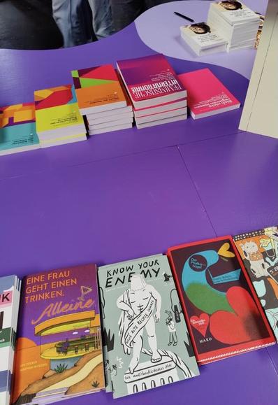 Unterwegs auf der Performativen Buchmesse in Hamburg: Auf einer lilafarbenen Tischfläche liegen Bücher von Dietz Berlin, im Vordergrund die Maro-Hefte vom Maro Verlag. Foto: kaffeeundzigaretten__ via Instagram