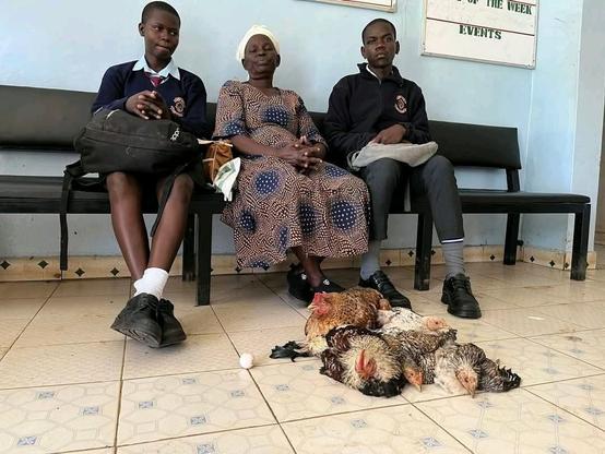 Grandmother and her two grandchildren with chicken brought as school fees.