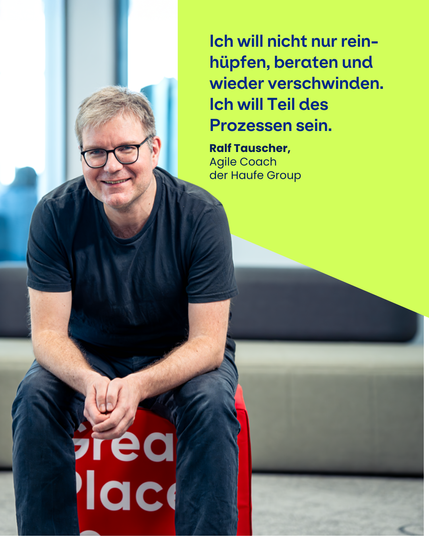 Zu sehen ist ein Mitarbeitender, der auf einem Würfel im Büro sitzt und das Zitat gibt: "Ich will nicht nur reinhüpfen, beraten und wieder verschwinden. Ich will Teil des Prozesses sein." Ralf Tauscher Agile Coach der Haufe Group.