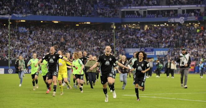 Werders Spielerinnen rennen nach Abpfiff jubelnd auf die Fotokamera zu, m Hintergrund ist das Innere des Volksparkstadions zu erkennen.