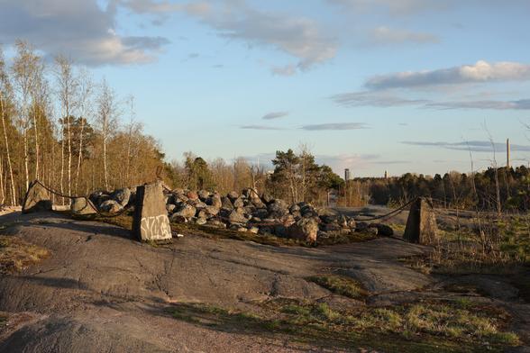 A photo of a Bronze Age cairn and the coastal cliffs in Meilahti on a sunny spring evening.