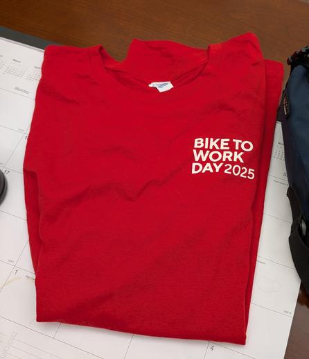 A Bike to Work Day T-shirt folded on a desk. It is red.