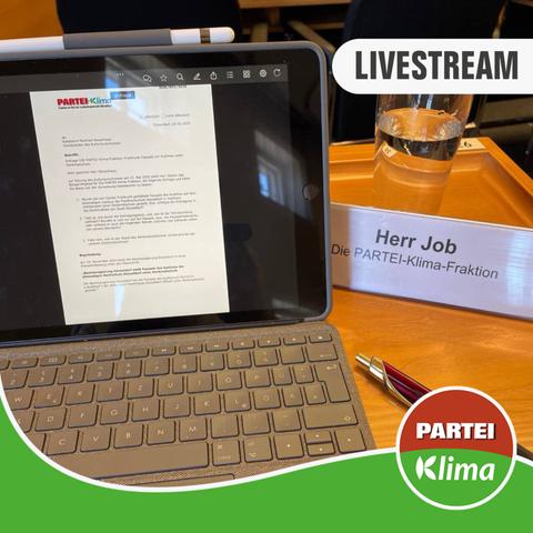 Zu sehen ist eine Nahaufnahme des Tisches von Stefan Job (Klimaliste) im Plenarsaal des Düsseldorfer Rathauses. Im Fokus ist der geöffnete Laptop mit unserem heutigen Antrag und ein Glas Wasser.
