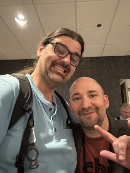 a selfie with a tall guy and a normal height guy throwing the horns
