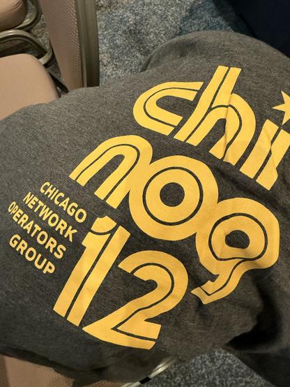 The CHINOG 12 shirt. It’s dark gray with gold
lettering with the text “chi nog 12 Chicago Network Operators Group”