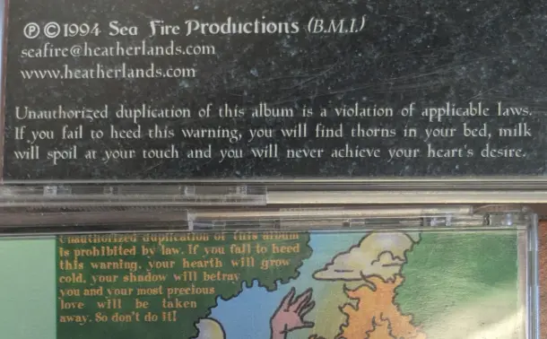 The backsides of two CD cases with dire warnings.