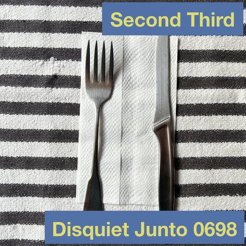 This photo shows a fork and a knife on a napkin, plus the name and number of the current Disquiet Junto project