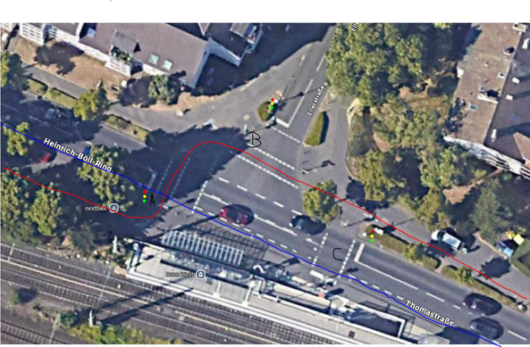 Satellitenbild der Kreuzung Heinrich-Böll-Ring / Ellerstraße in Bonn.

Der Fahrradweg verläuft zunächst parallel zur Straße Richtung Innenstadt, wird dann aber über eine Ampel auf die andere Straßenseite geleitet, wo es einen Radweg gibt, der in beide Richtungen freigegeben ist. Auf der Straße ist Richtung Innenstadt aber auch ein Schutzstreifen eingezeichnet, auf den ich gerne wechseln möchte. Das Problem besteht darin, dass entweder die Autos auf der Hauptstraße grün haben und ich mich nur schwer in den fahrenden Verkehr einfädeln könnte (die Fußgängerampel wäre ja auch rot) oder die einbiegenden Autos aus der Ellerstraße grün haben, die nicht mit Verkehr rechnen, weil meine Seite dann ja rot hat.