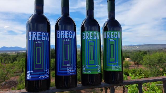 Quatre botelles del vi Brega 2023 a damunt un arrambador. La Serra de Tramuntana es veu al fons.