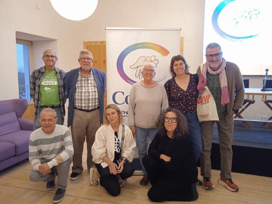 Diverses persones, representants d'organitzacions de l'economia social i solidària de Mallorca, posen per a una foto de grup davant el logo de l'Estalvi Ètic de Colonya.