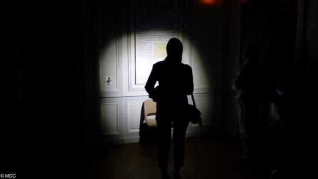 Une femme visite un musée, munie d’une lampe-torche. Photographie © MCC
