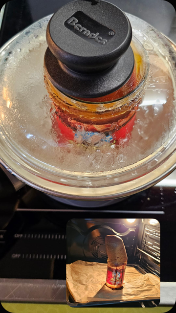 Das Bild zeigt eine Kochtopfdeckel mit dem Markennamen "Berndecs" in der Mitte, der auf einem Herd platziert ist. Der Deckel ist mit feinen Wassertröpfchen bedeckt, was darauf hinweist, dass der Inhalt des Topfes kocht. Unterhalb des Hauptbildes befindet sich ein kleineres Bild, das einen Topf mit einer Hupsi Curry-Vorrichtung im Ofen zeigt. Die Vorrichtung besteht aus einer Flasche, die auf Papier in einem Ofenrost steht. Die Flasche enthält eine rote Flüssigkeit, vermutlich Curry, und scheint in einem Backprozess zu sein.