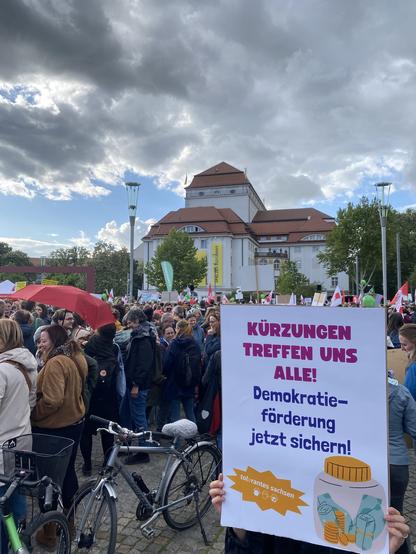 Demonstration. Schild: „Kürzungen treffen uns alle! Demokratieförderung jetzt sichern!“
