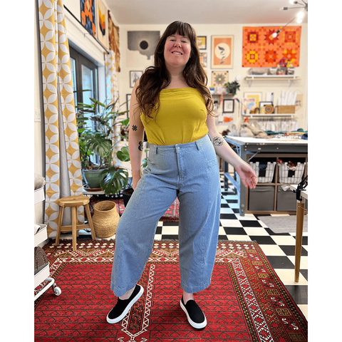 Helen wears light wash barrel leg jeans and a yellow top.