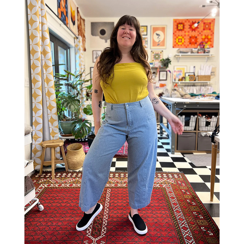 Helen wears light wash barrel leg jeans and a yellow top.