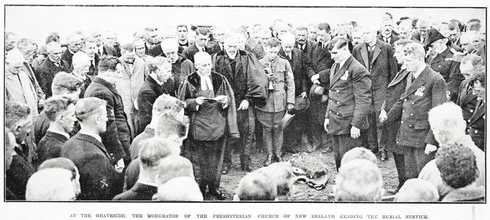 Black-and-white photo: At the Graveside: The Moderator of the Presbyterian Church of New Zealand Reading the Burial Service. 1925. Description: A formally dressed group, mainly if not all men, stand around the barely visible grave. The group includes several in military dress uniforms. Citation: Supplement to the Auckland Weekly News, 21 May 1925, p. 44. Auckland Libraries Heritage Collections AWNS-19250521-44-02. https://kura.aucklandlibraries.govt.nz/digital/collection/photos/id/243931