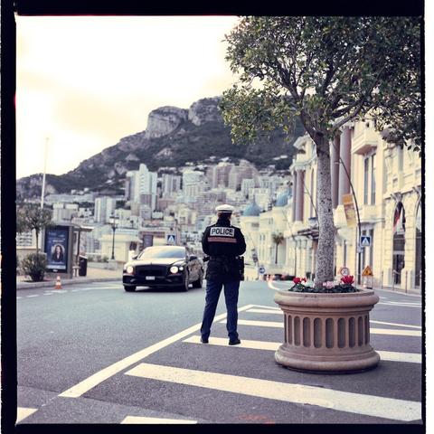 A police officer standing at an intersection, directing traffic, set against a backdrop of buildings, in Monte Carlo.