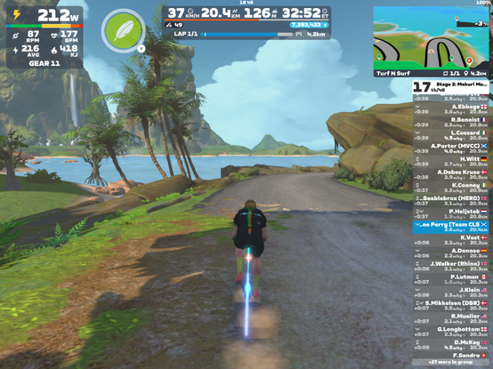 Screenshot from Zwift with a cyclists avatar in Team CLS kit racing alone, with the ocean and forested tropical islands beyond.
