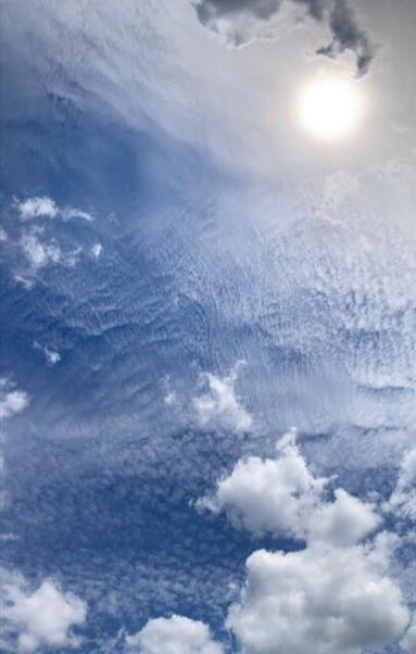 Blauer Himmel mit dramatischen Wolken. Die Sonne mit Halo. Aufnahme mit Panormafunktion gemacht.