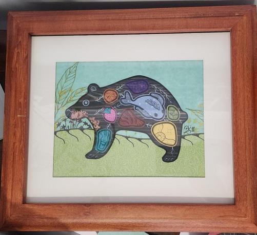 Mixed media artwork by Danilynn Jiibay (2025). Depiction of a bear out in the woods. Their insides consist of various items ranging from their clan roles to fish to berries.