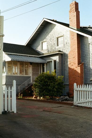 Afternoon light and shadow drapes in a diagonal fashion over the west face of a  turn of the century craftsman house.