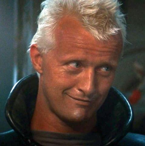 Rutger Hauer as Roy Batty smirks at someone just off screen.