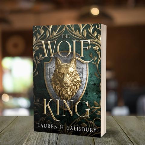 Green and gold cover of The Wolf King by Lauren H. Salisbury, which has a shield with a gold wolf head on the front.