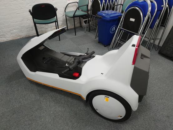 A top down picture of the Sinclair C5 from the side fully assembled and cleaned, sitting on a carpeted floor, the POD LEDs lit up.