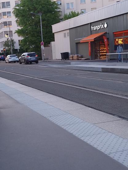 Voitures garées sur un terre-plein entre la chaussée et la voie de tram.