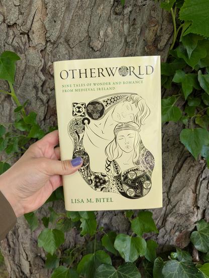 Holding the book "Otherworld - Nine Tales of Wonder and Romance from Medieval Ireland" by Lisa M. Bitel in front of a tree