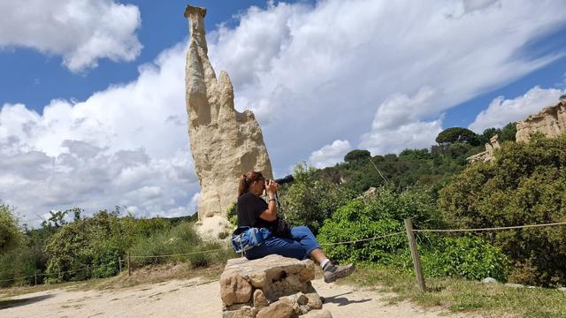 Artist Francoise Vaal photographing rugged rocks in a natural environment.