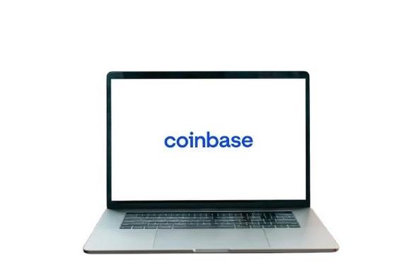 A laptop displaying the Coinbase logo on a white screen.