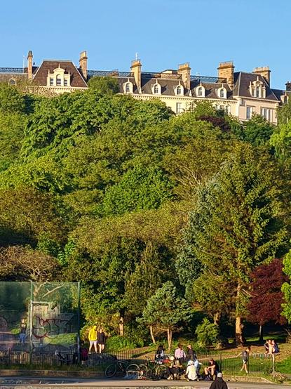 A row of French Renaissance style Victorian townhouses rising above a large urban park in Glasgow.