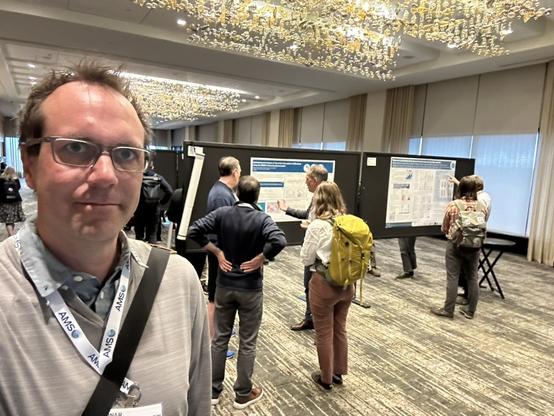 selfie with people standing in front of scientific posters in poster session in background