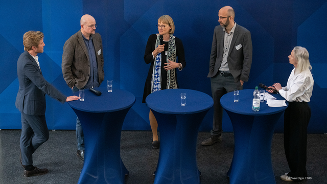 Foto von Benedikt Fecher (Wissenschaft im Dialog), Prof. Dirk Brockmann (TUD), Beatrice Lugger und Prof. Sven Engesser (TUD) bei einer Diskussionsrunde an Stehtischen, die von Marion Schmidt (CCO der TUD) moderiert wurde (v. l. n. r.).