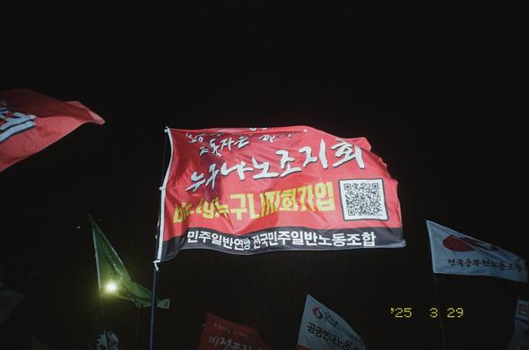 민주일반연맹 전국민주일반노동조합 누구나노조지회 깃발이 휘날리던 도중 플래시 불빛을 받아 어둠속에서 선명하게 찍혔다.