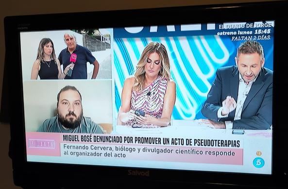 Captura de una imagen emitida en Telecinco. El biólogo Fernando Cervera es puesto en directo frente a un charlatán. Titular: "Miguel Bosé denunciado por promover un acto de pseudoterapias".