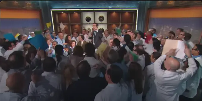 Fotograma del programa de Last Week Tonight. Se ve a 97 científicos mostrando informes y pruebas a tres negacionistas del cambio climático. John Oliver, el presentador, trata de poner orden en el caos.