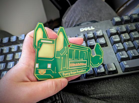 Hand holding a real printed circuit board of the design in the previous image in front of a keyboard. The name "CZGoldEdition" has been added in copper solder.