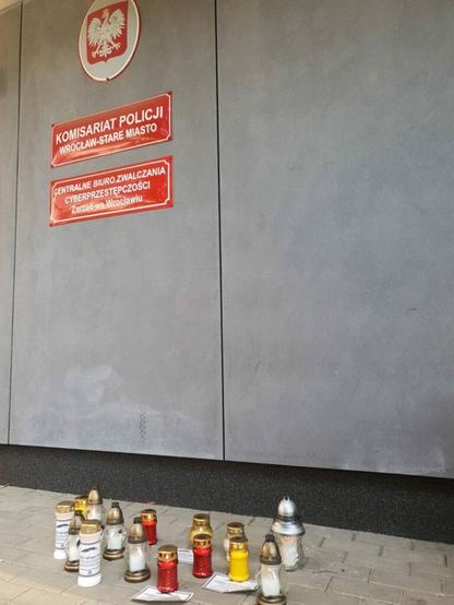 Zdjęcie przedstawia znicze pod komisariatem.