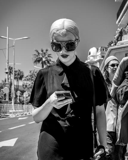 Lady in black with sun glasses in the street watching her smartphone