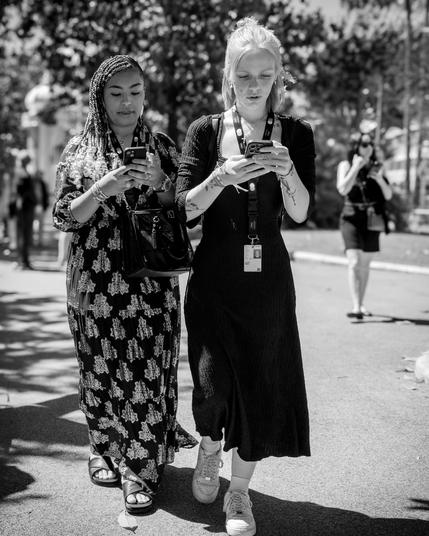 Two ladies in the street watching their smartphones