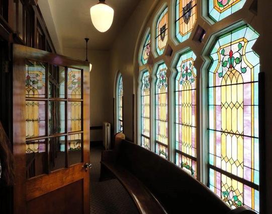 Church transept highlighting multiple stained glass windows reflected in wide nave doorway glass