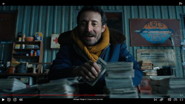 Screenshot of the show showing a still of a man counting money with the play controls enabled showing the episode title and time bar. In the shot, there’s a sign on the wall in the background, slightly out of focus reading "Yuri’s Fish n' Fly"