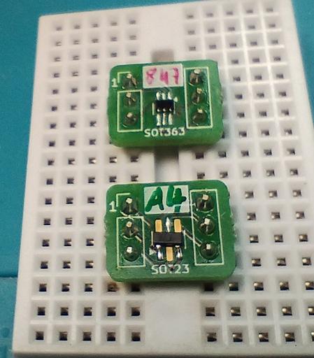 two of the boards with soldered components. the top one has a dual NPN/PNP transistor BC847 BPN, and the lower one has a BAV70 dual diode. the area for the label is a bit small, so they only have "847" and "A4" written. the two boards are inserted into a solderless breadboard, bridging the gap in the middle, so the pins can be accessed on either side.